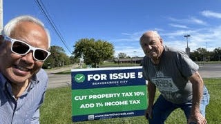 Two supporters with a For Issue 5 yard sign
