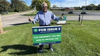 A supporter giving a thumbs-up next to a For Issue 5 yard sign